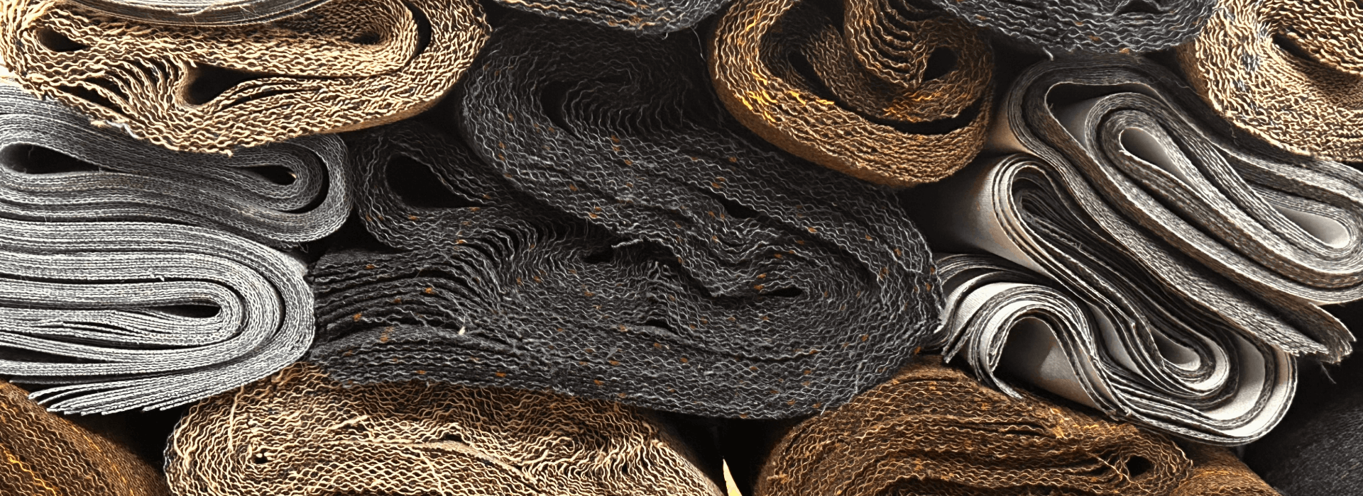 Stack of various textured fabric swatches in neutral colors.